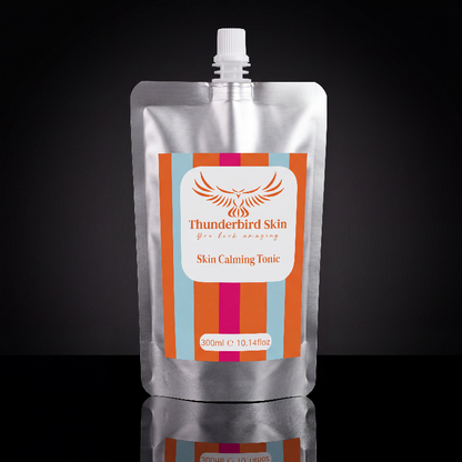 A 300ml silver foil pouch of Thunderbird Skin Skin Calming Tonic with a white cap, set against a dark reflective background.